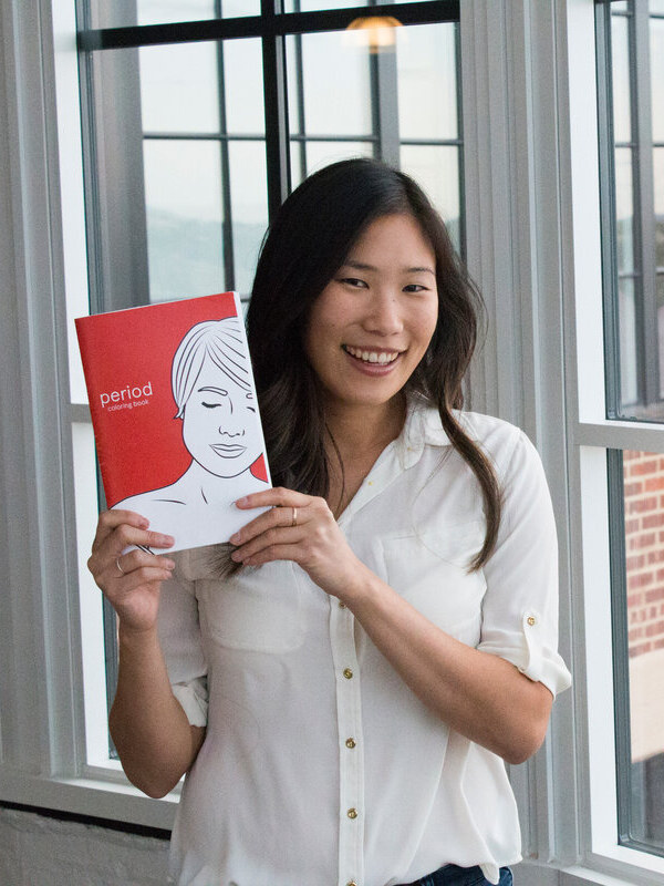 Andrea Yip holding a copy of the red Period Coloring Book