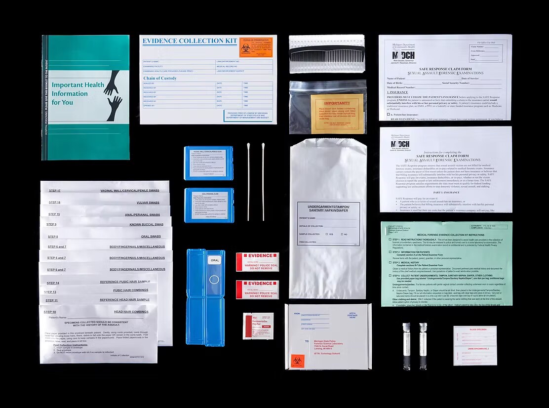 The contents of a sexual assault evidence collection kit laid out on a black background